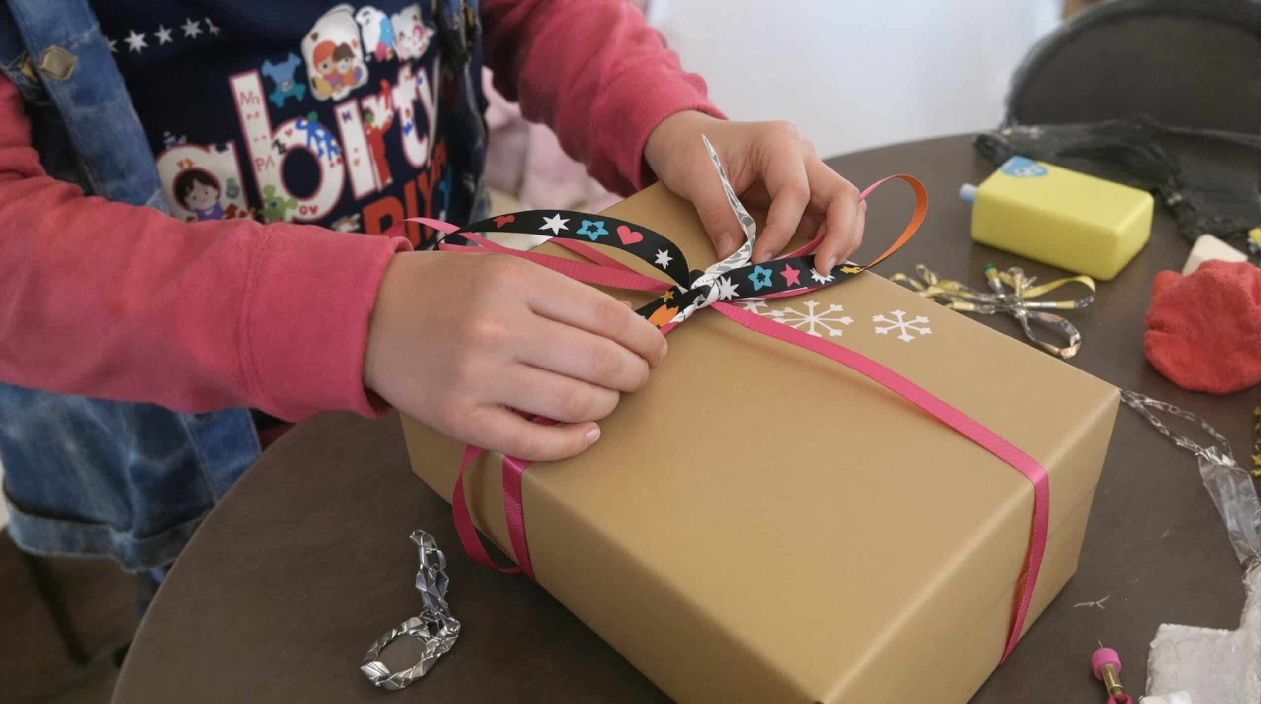 Een kind pakt een zelfgemaakt cadeau in