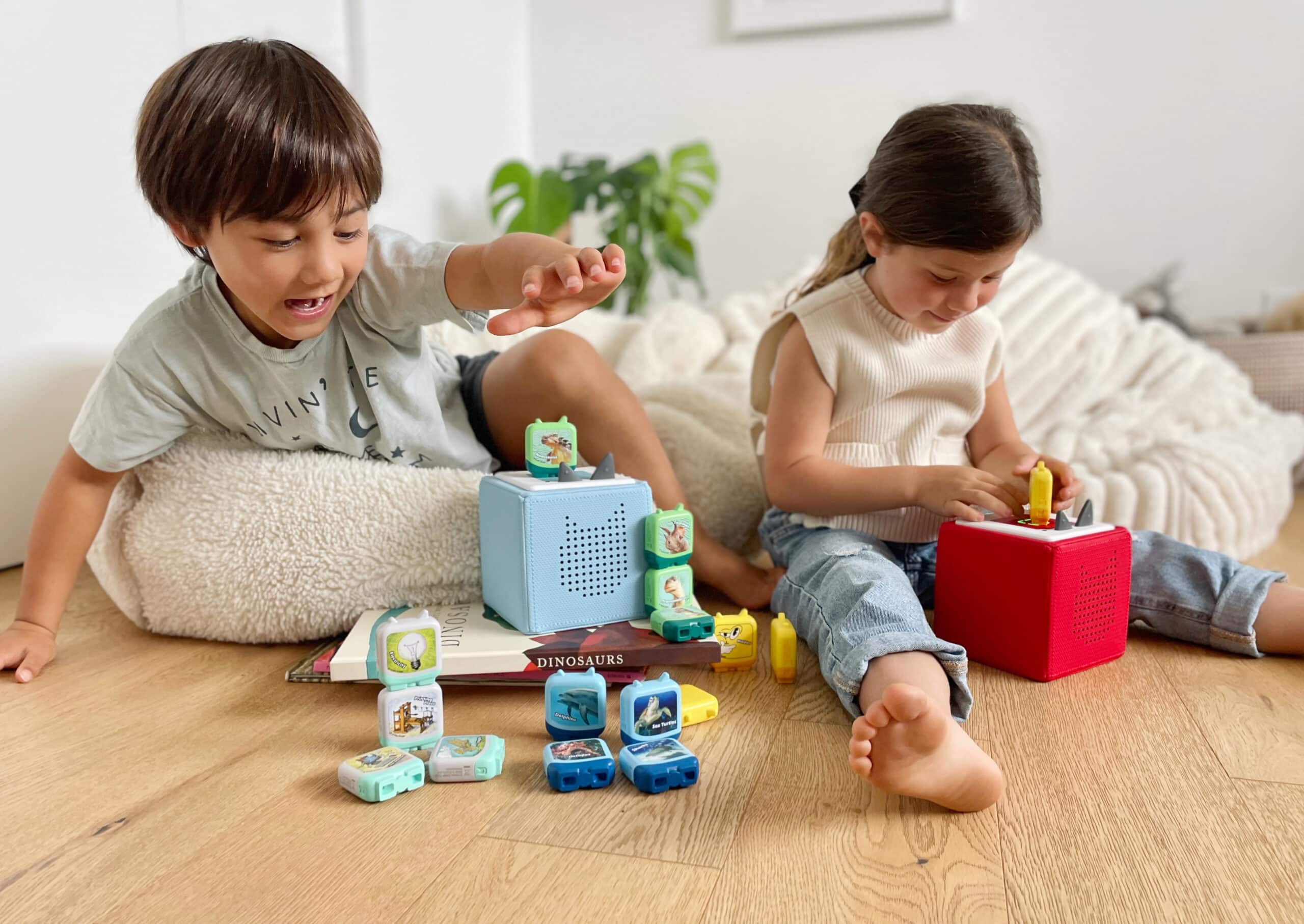 Twee kinderen zitten in een kinderkamer te luisteren naar Tonies op hun Toniebox.